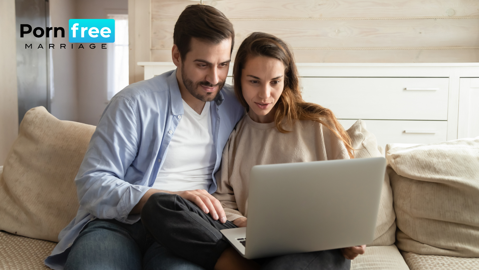 Couple sitting on a couch close looking at laptop
